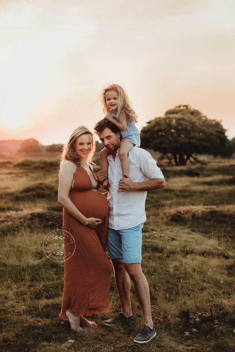 gezinsfoto tijdens de zwangerschapsfotoshoot op de heide met zonsondergang.